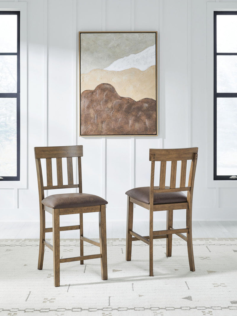 Set of 2 light brown barstools with dark upholstered seats and slatted backs.