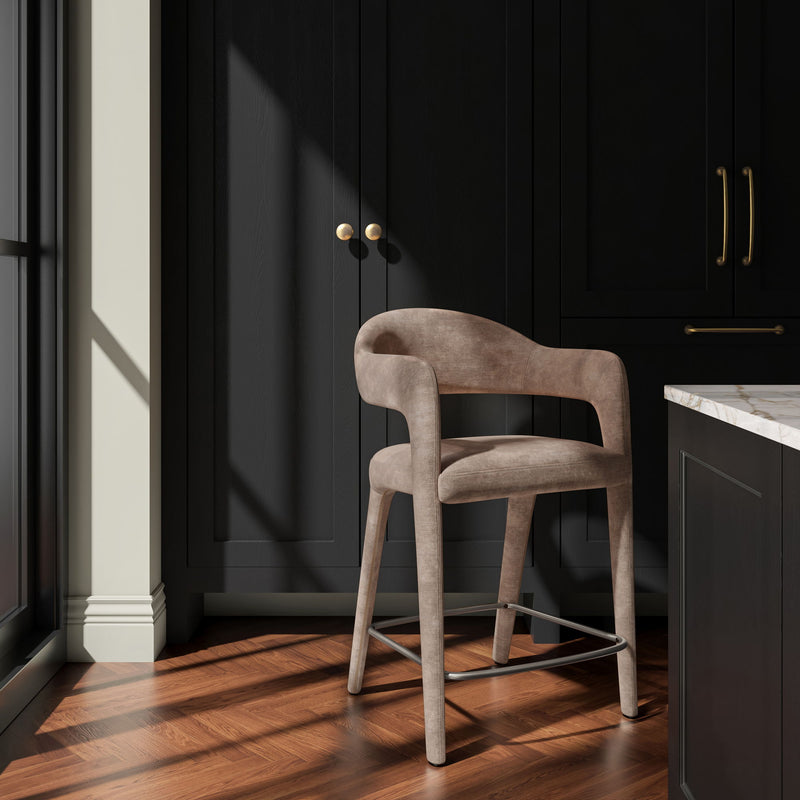 Martens camel counter stool shown from an angle, with upholstered arms and a metal footrest.
