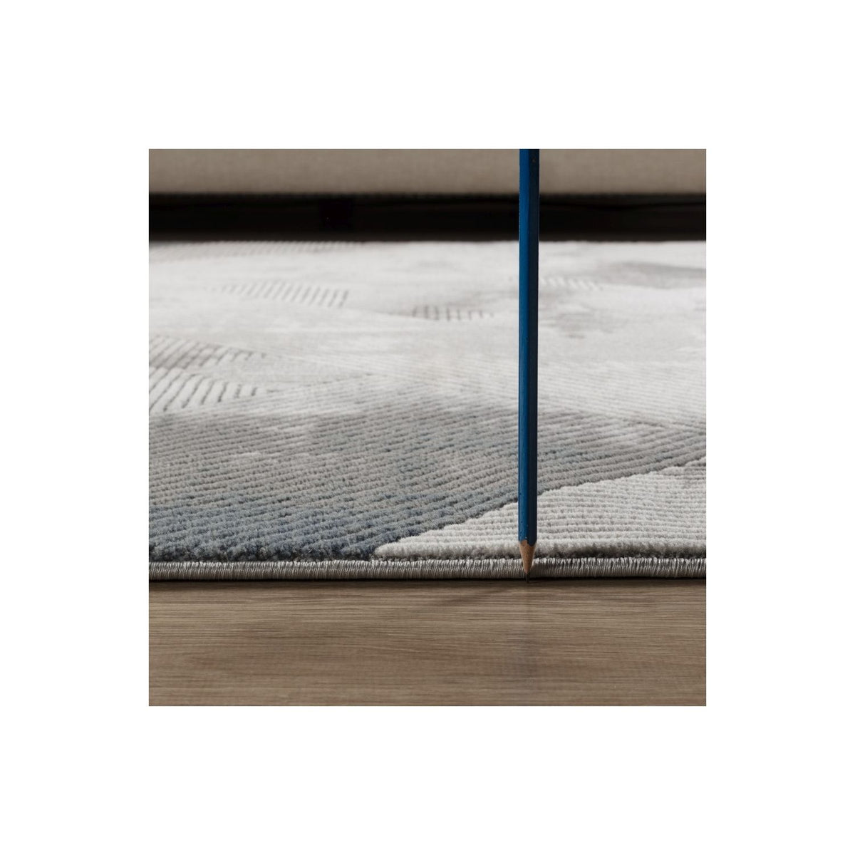 Gray geometric rug edge detail with textured pile and stitched border