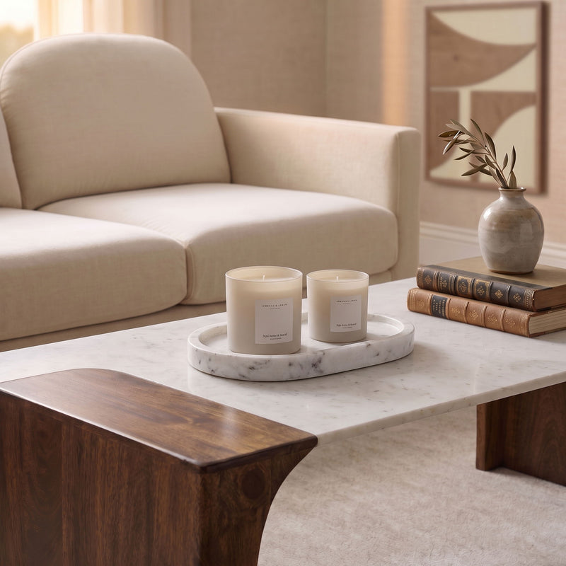 Round marble tray holding two white candles on a table.