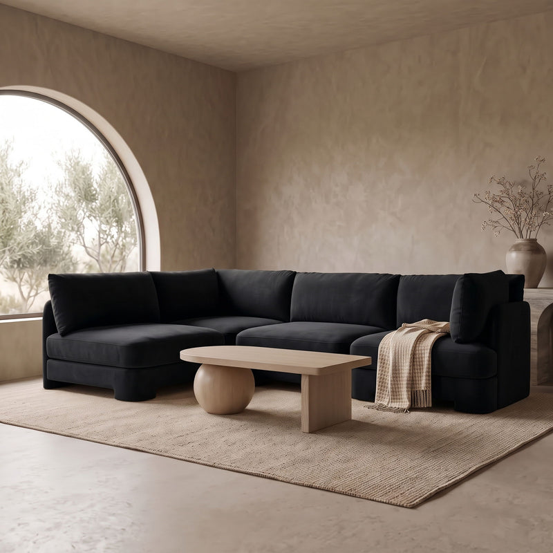 Black velvet armless sectional sofa with rounded arms and tufted cushions