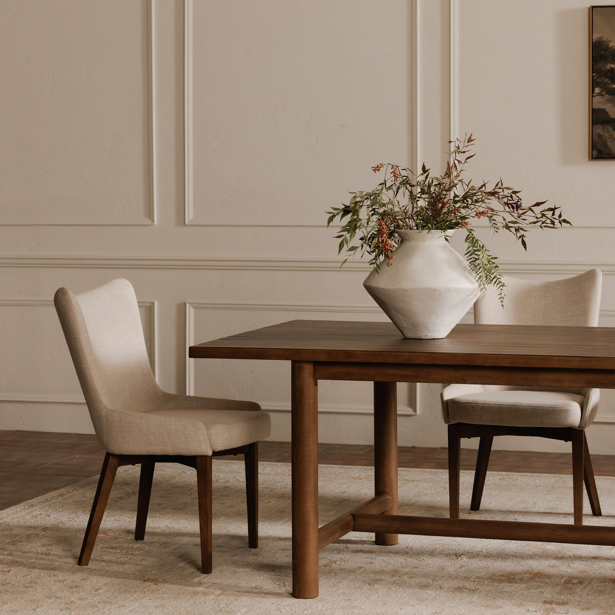 Side view of a beige upholstered dining chair with tapered dark wood legs