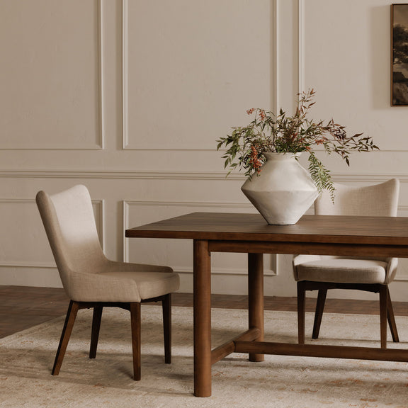 Side view of a beige upholstered dining chair with tapered dark wood legs