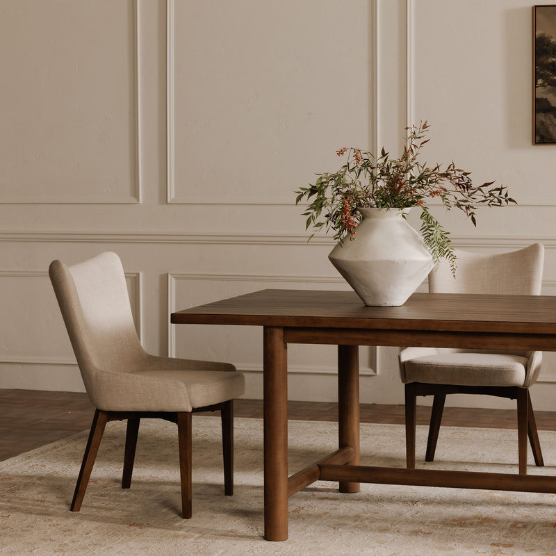 Side view of a beige upholstered dining chair with tapered dark wood legs