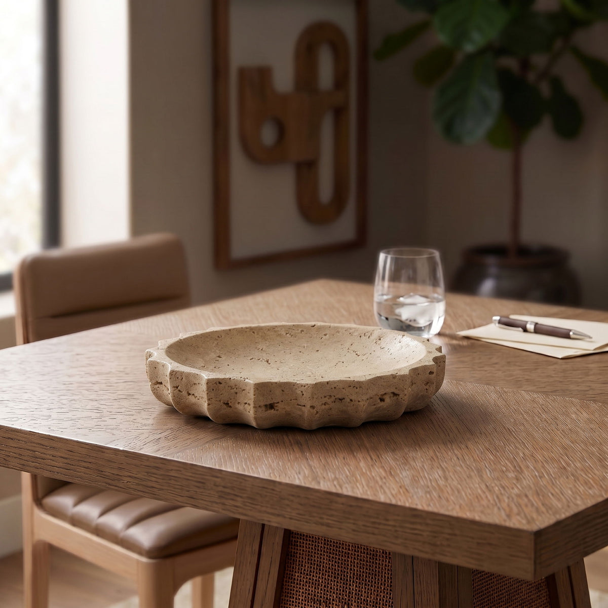 Beige travertine serving bowl on a wooden table, scalloped rim visible.