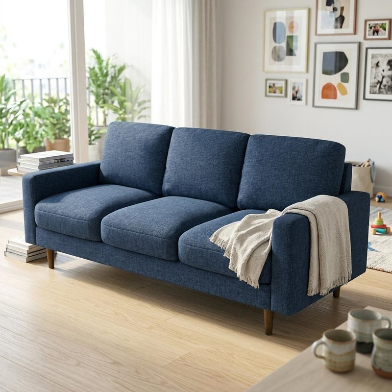 Three-seat dark blue fabric sofa with loose back cushions, broad arms, and tapered wood legs.