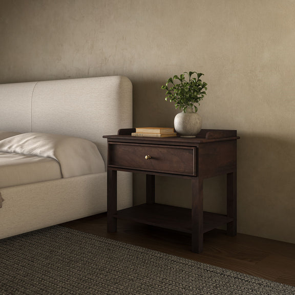 Dark brown wooden nightstand beside a bed, with a drawer, lower shelf and raised top edge