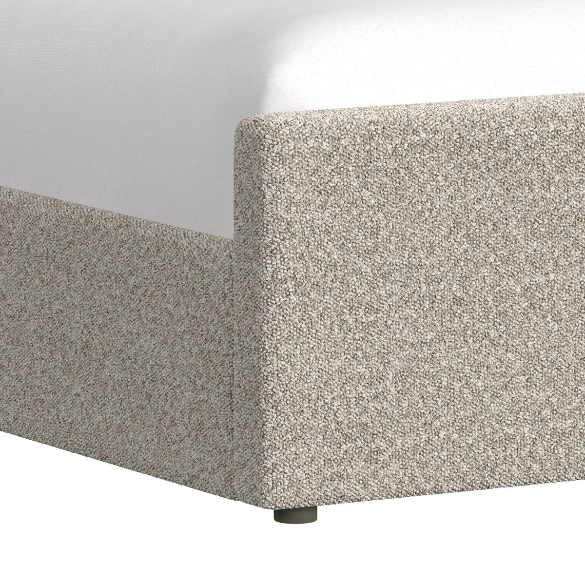 Light gray upholstered bed corner detail with textured fabric and tapered legs