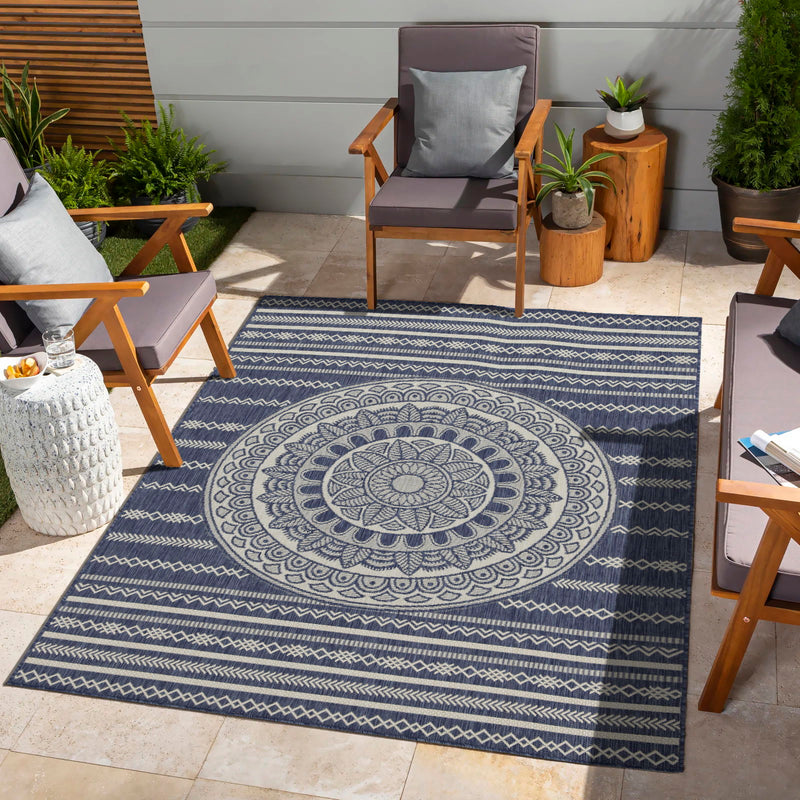 Indoor/outdoor area rug with dark blue and light blue circular medallion and border stripes