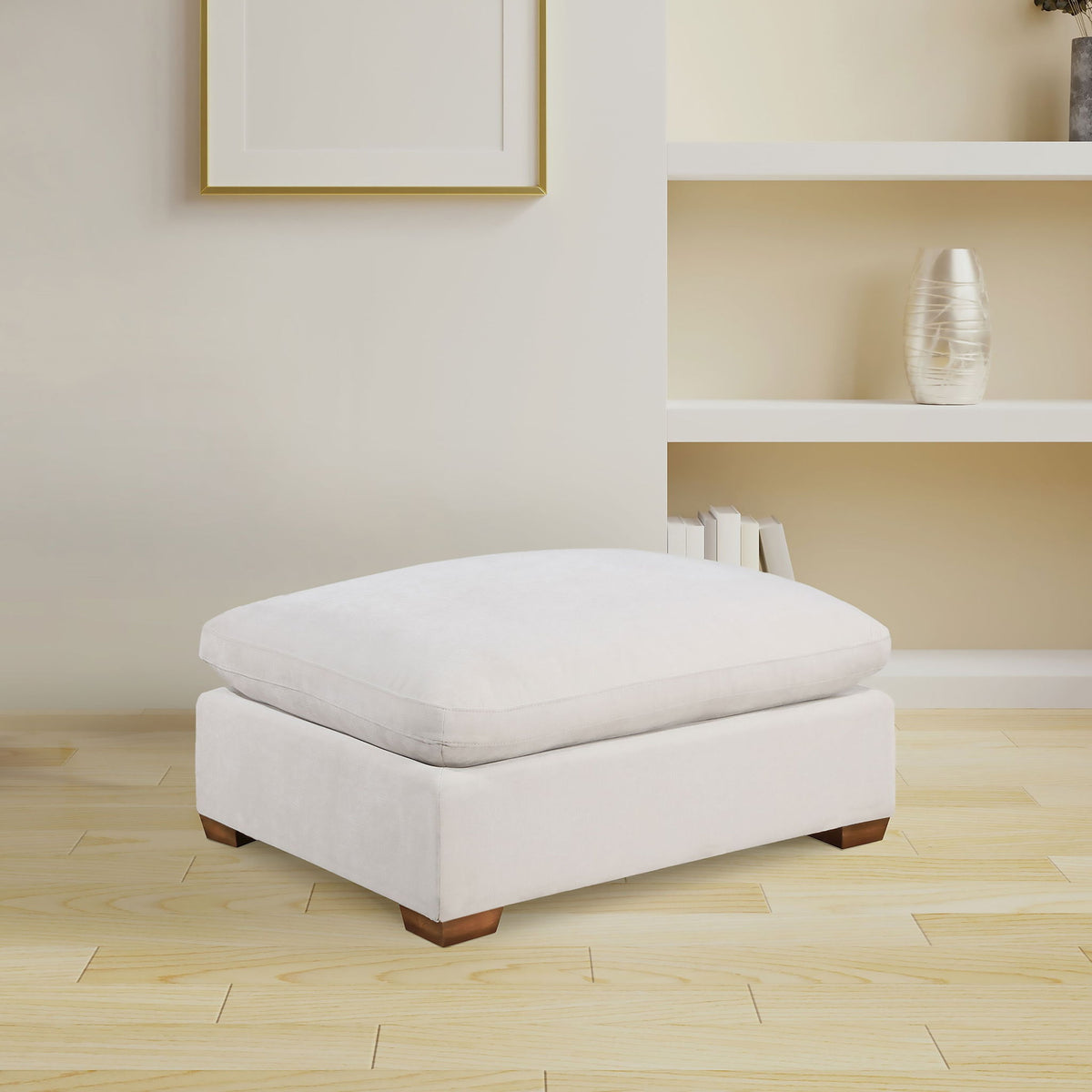 White upholstered ottoman with tufted-look top and wooden block feet.