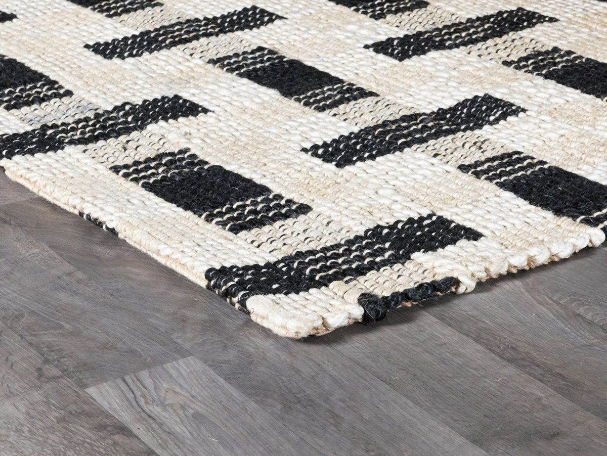 Ivory and black geometric rug with interlocking rectangular blocks, corner detail