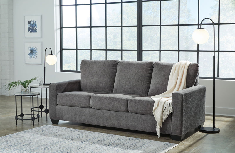 Gray fabric sofa with three seat cushions and white blanket draped over arm