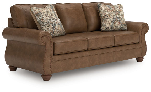 Dark brown sofa with padded arms and patterned accent pillows, stitched seat panels