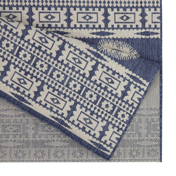 Close-up of blue and white polypropylene rug with geometric border and medallion motifs