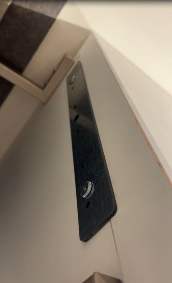 Beige cabinet drawer side with black metal hardware and recessed pull