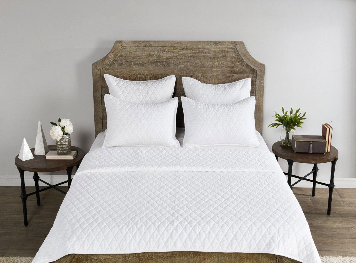 White quilt with diamond quilting pattern and pillow shams on bed
