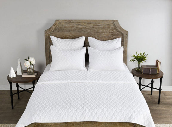 White quilted decorative shams with diamond stitch pattern, two on top
