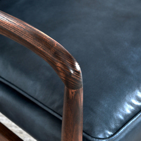 Kiannah club chair close-up: blue upholstered cushion and rounded wooden armrest