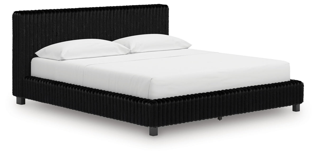 Black upholstered bed frame with ribbed headboard and white duvet and pillows.