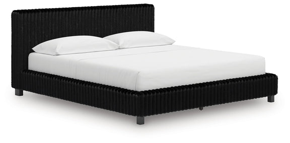 Black upholstered bed frame with ribbed headboard and white duvet and pillows.