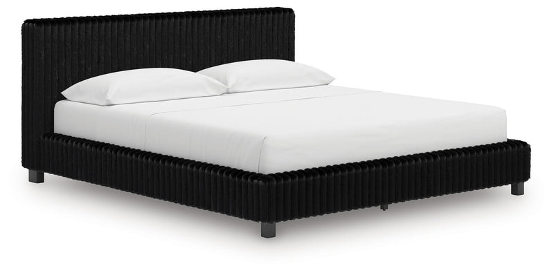 Black upholstered bed frame with ribbed headboard and white duvet and pillows.