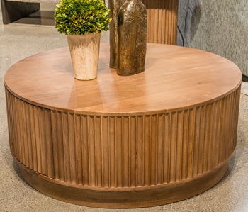 Light brown round wooden coffee table with smooth tabletop and fluted barrel base