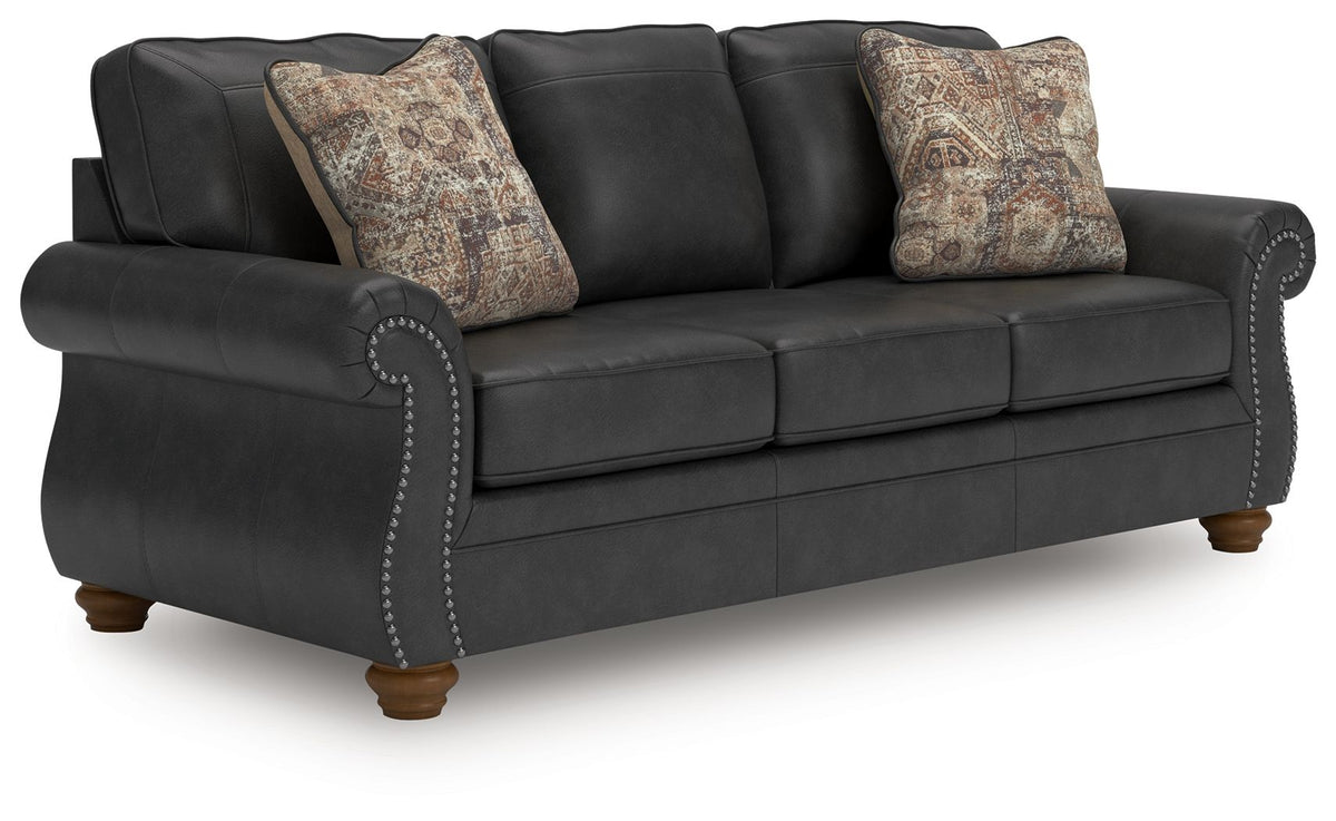 Dark gray sofa with tufted arms and two patterned throw pillows