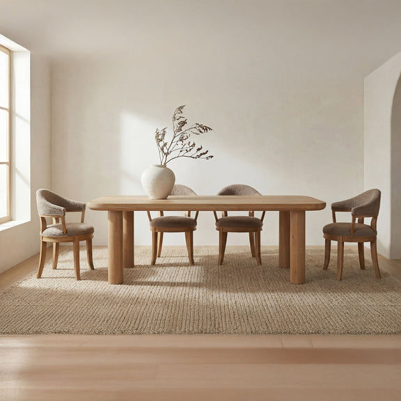 Natural large dining table with rounded top and four sturdy legs, styled with chairs