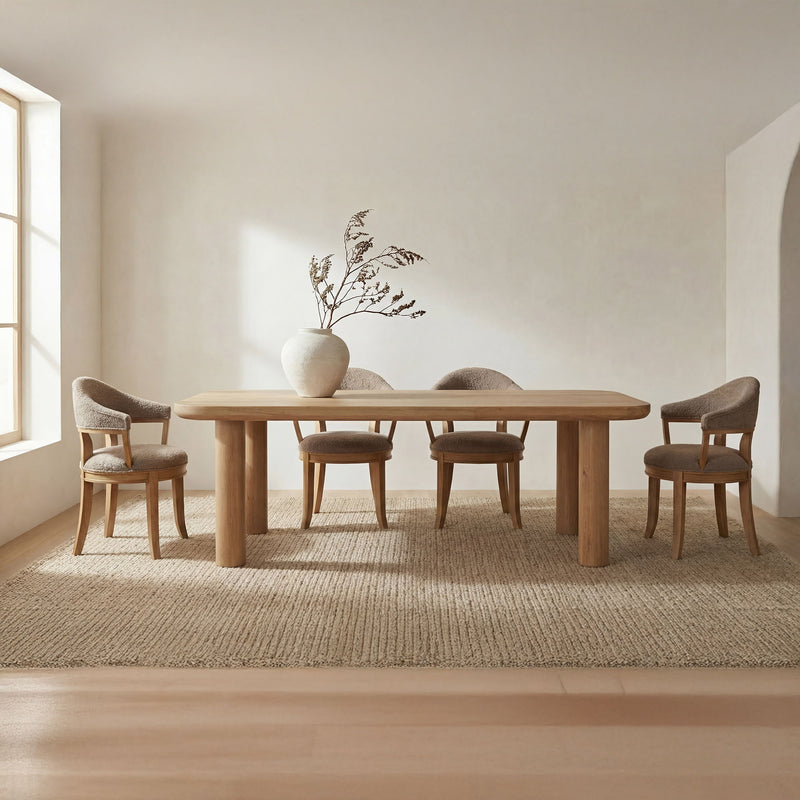 Natural large dining table with rounded top and four sturdy legs, styled with chairs