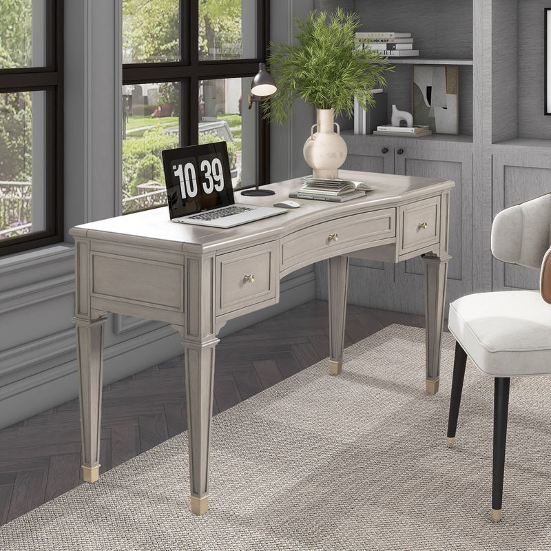 Gray executive desk with three drawers, tapered legs, and brass hardware