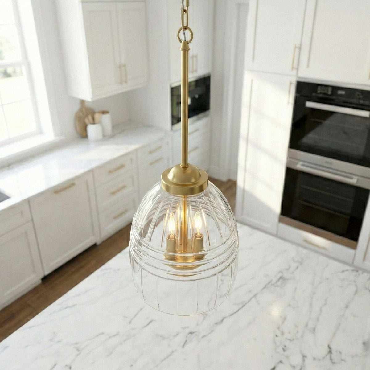 Clear glass dome pendant with gold top and three candle-style bulbs on a chain