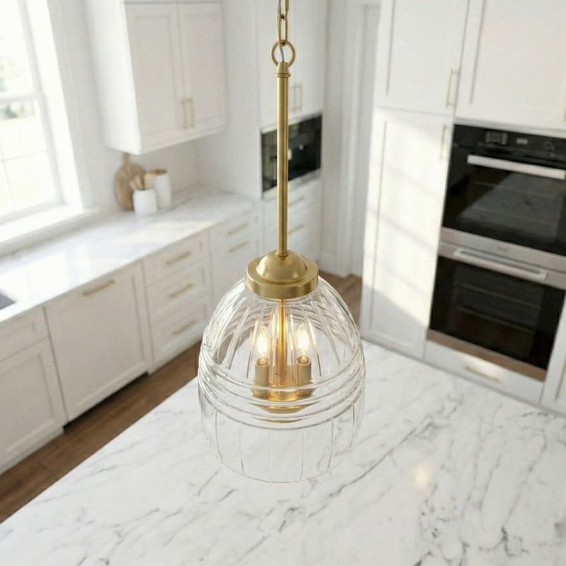 Clear glass dome pendant with gold top and three candle-style bulbs on a chain