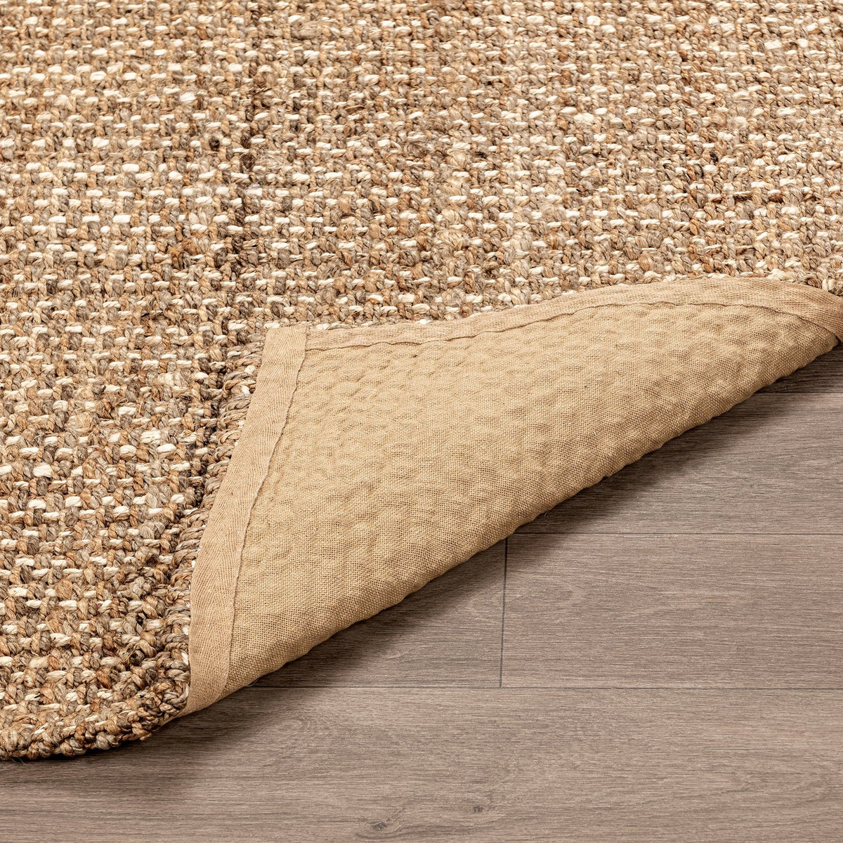 Woven jute rug corner detail with turned-under edge on gray floor