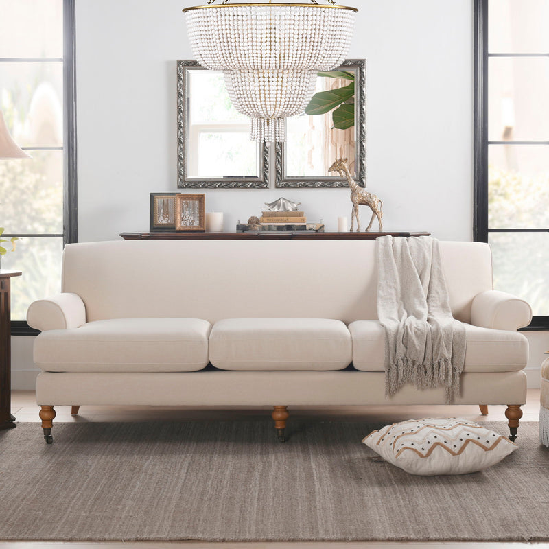 Modern three-cushion tightback sofa in off-white fabric, with draped throw and one cushion