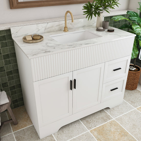 White bathroom vanity with fluted front, single sink and gold faucet, two doors, drawer