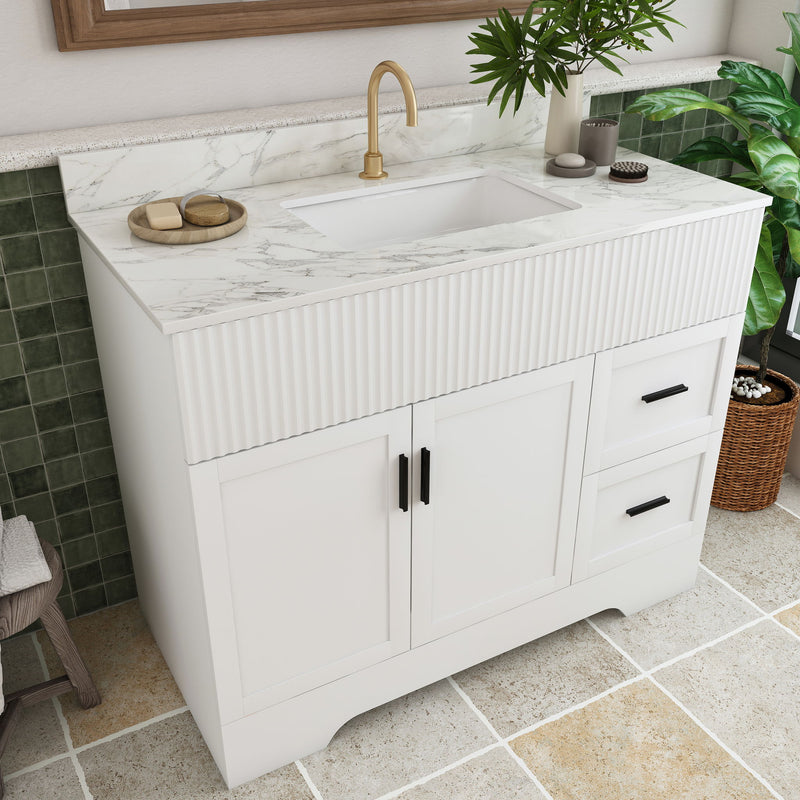 White bathroom vanity with fluted front, single sink and gold faucet, two doors, drawer