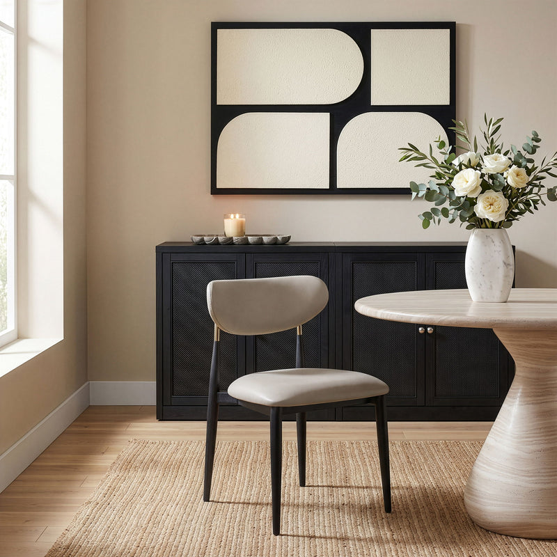 Cream vegan leather dining side chair, three-quarter view with padded seat and rounded back, black legs
