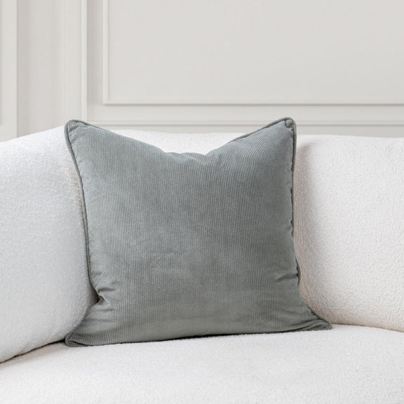 Gray-green accent pillow on sofa, textured fabric and corded edge