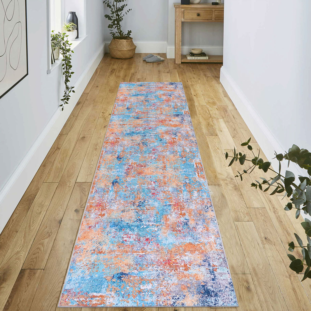 Washable runner rug with light blue and orange abstract pattern on floor