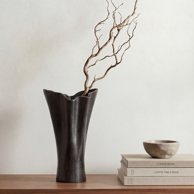 Black cast aluminum vase with flared top, styled with bare branch stems.
