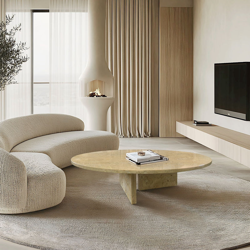 Round beige stone coffee table in living room, with unique veining and sculpted base.