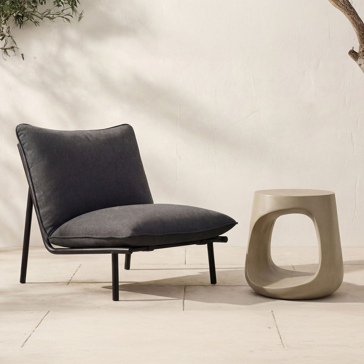 Cream sculptural outdoor stool with oval cutout opening, tapered sides and flat top.