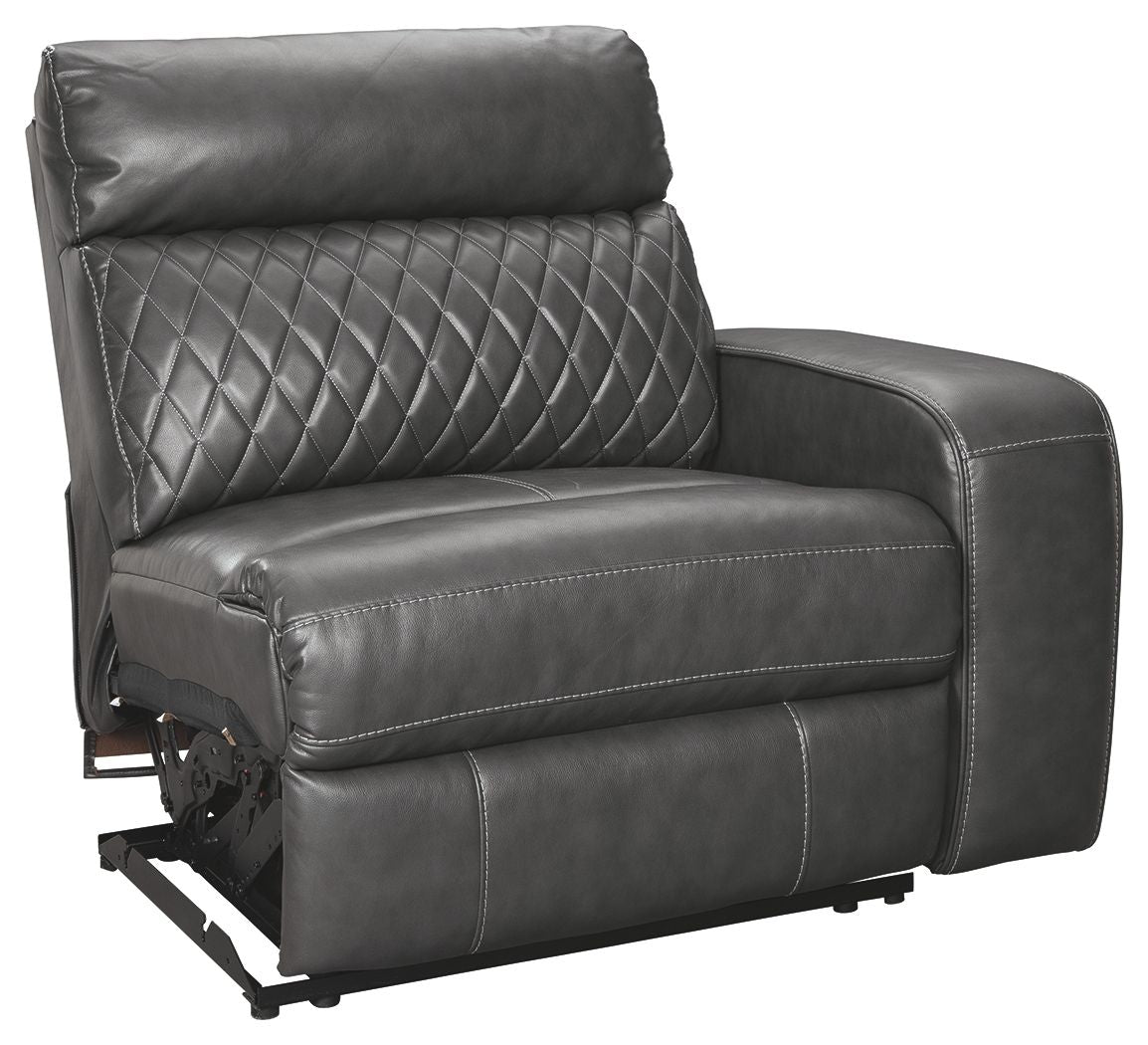 Gray power recliner seat with diamond-quilted back, padded arms, and exposed power hardware