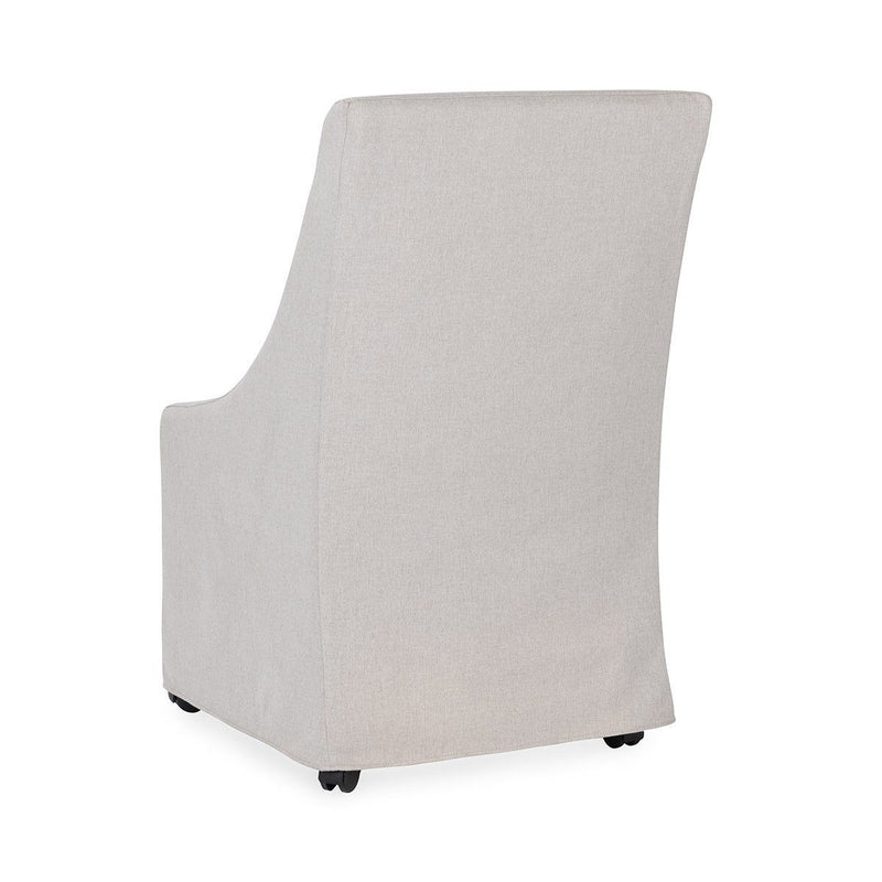 Upholstered rolling dining chair in light beige fabric, side view with casters