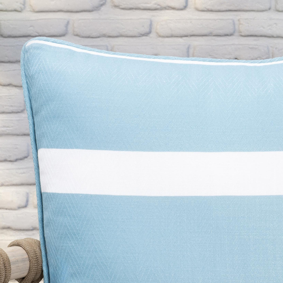 Blue striped throw pillow close-up with white band and piped edge