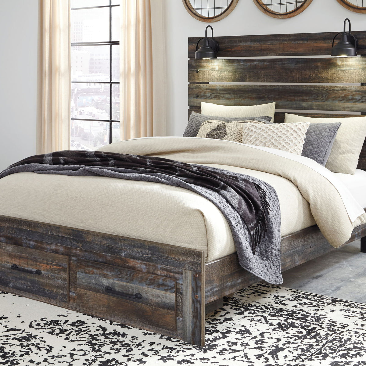 Drystan panel bed with dark wood headboard, two front drawers, and layered neutral bedding.