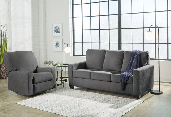 Dark gray sofa and matching armchair set with padded arms and neutral throw blankets
