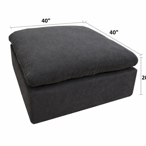 Dark gray upholstered ottoman with square base and rounded, padded top
