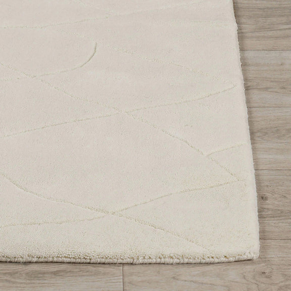 Ivory wool rug corner with low-pile edge and softly textured surface