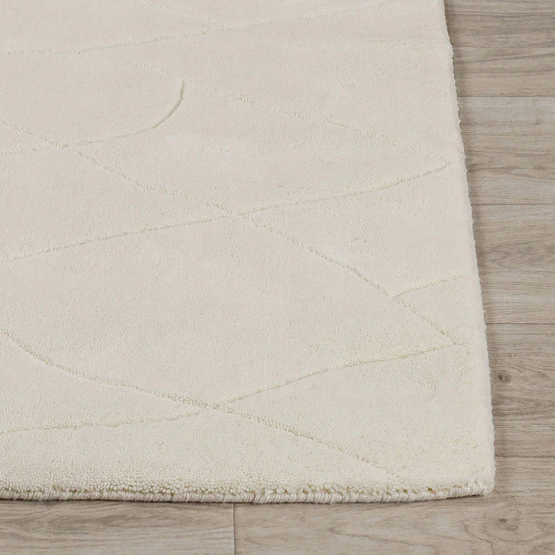 Ivory wool rug corner with low-pile edge and softly textured surface